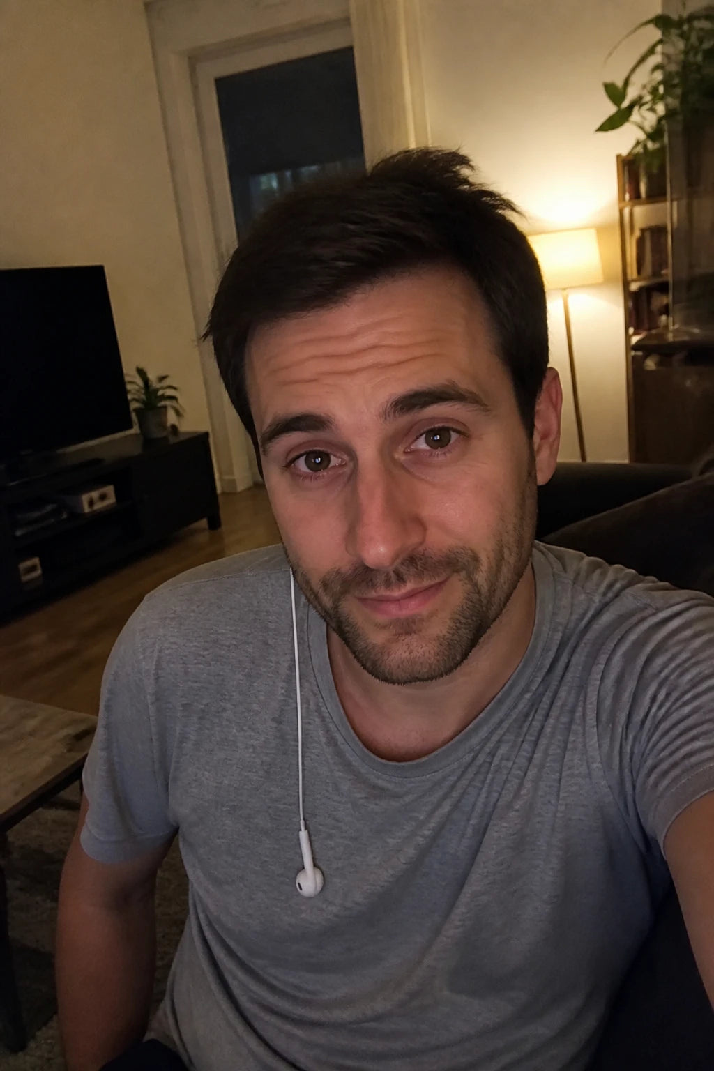 Selfie von Tom abends auf dem Sofa, nachdenklicher halb-ertappter Blick, ein Kopfhörer baumelt